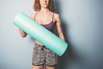 Athletic young woman is holding a foam roller for exercise